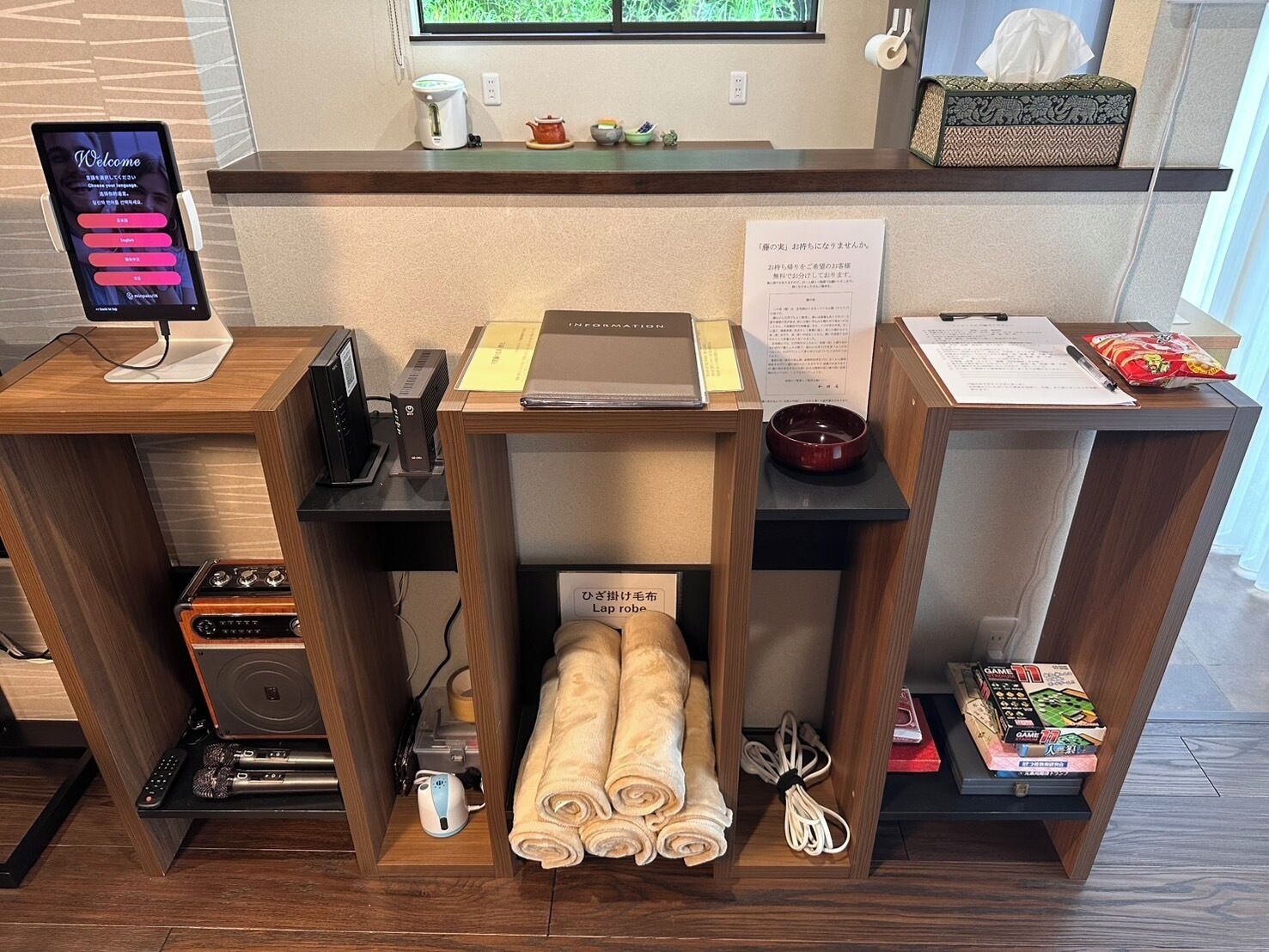 A reception desk with a digital screen, a kettle, a tea set, a tissue box, a bowl, and a Game 11 board game.