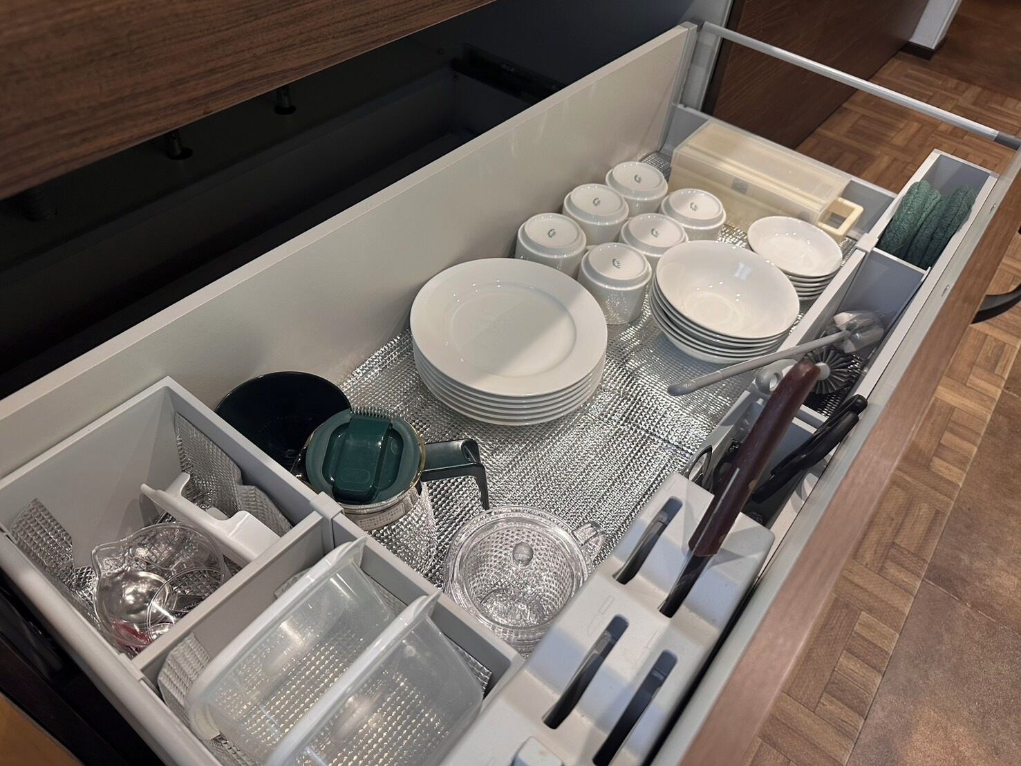 Un cajón ordenado con utensilios de cocina, como platos, tazones y cubiertos.