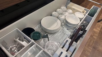 Un cajón ordenado con utensilios de cocina, como platos, tazones y cubiertos.