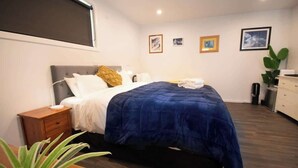 A bedroom with a bed, bedside table, and a plant. - Custom Cabin -  In Town - Hot Tub - Super King Bed (Queenstown)