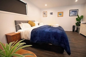 A bedroom with a bed, bedside table, and a plant.