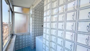 Una habitación con un ventanal grande, suelo de baldosas y una pared llena de cajas.