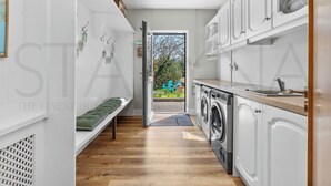 A modern kitchen with a built-in washing machine, a bench, and a view of the garden. - Owenmore Lodge 3 bedroom home (County Kerry)