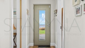 A hallway with a wooden floor, a green door, and a view of the sea through the door. - Owenmore Lodge 3 bedroom home (County Kerry)