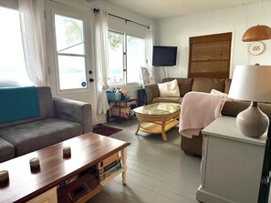 Una sala de estar con un sofá, una mesa de centro, un televisor y una lámpara.