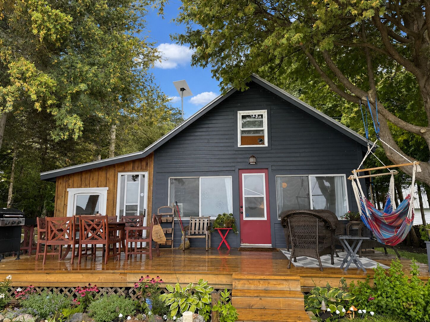 A house with a deck, outdoor furniture, and a hammock.