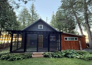 A modern house with a glass entry door, a wooden exterior, and a welcome sign.