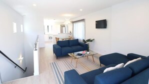 A modern living room with a sofa set, a coffee table, and a TV mounted on the wall.