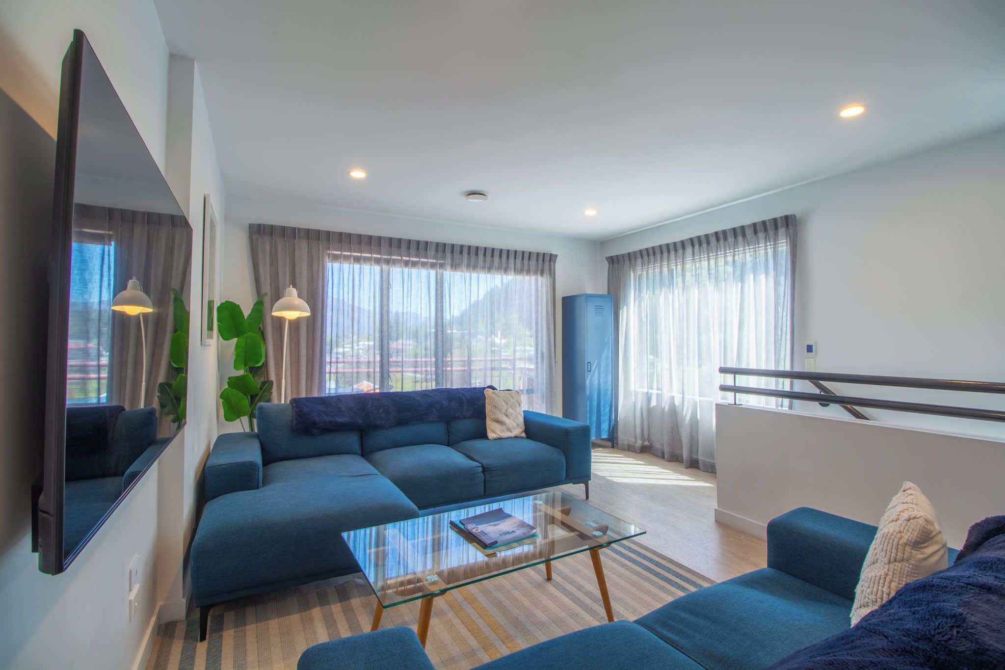 A modern living room with a sofa, a glass coffee table, and a blue armchair.