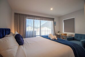 A hotel room with a large bed, a desk, and a chair. - Central Qt - Lake Views - Hot Tub - King Bed (Queenstown)