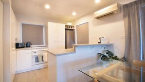 A modern kitchen with white cabinetry, a built-in oven, a microwave, and a glass dining table.
