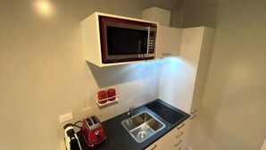 Une petite cuisine équipée d’un four à micro-ondes, d’un grille-pain et d’un évier.