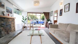 Ein modernes Wohnzimmer mit einem Glastisch, einem beige gefärbten Sofa und einem Kamin aus Stein.