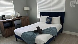 Un dormitorio con cama, mesita de noche, lámpara y unidad de aire acondicionado.