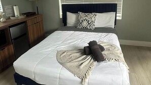 Un dormitorio con cama, escritorio y ventana con persianas.