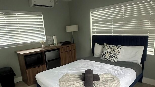 Un dormitorio con una cama, un escritorio y una silla. Hay un equipo de aire acondicionado en la pared.