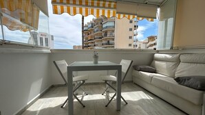 A balcony with a table and chairs, a sofa, and a view of buildings in the background. - Erisa 1, 47 - Studio with Terrace, Pool, Parking, 2nd line beach (Torremolinos)