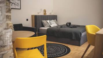 Un dormitorio moderno con una cama, una mesa de comedor redonda y una silla amarilla.