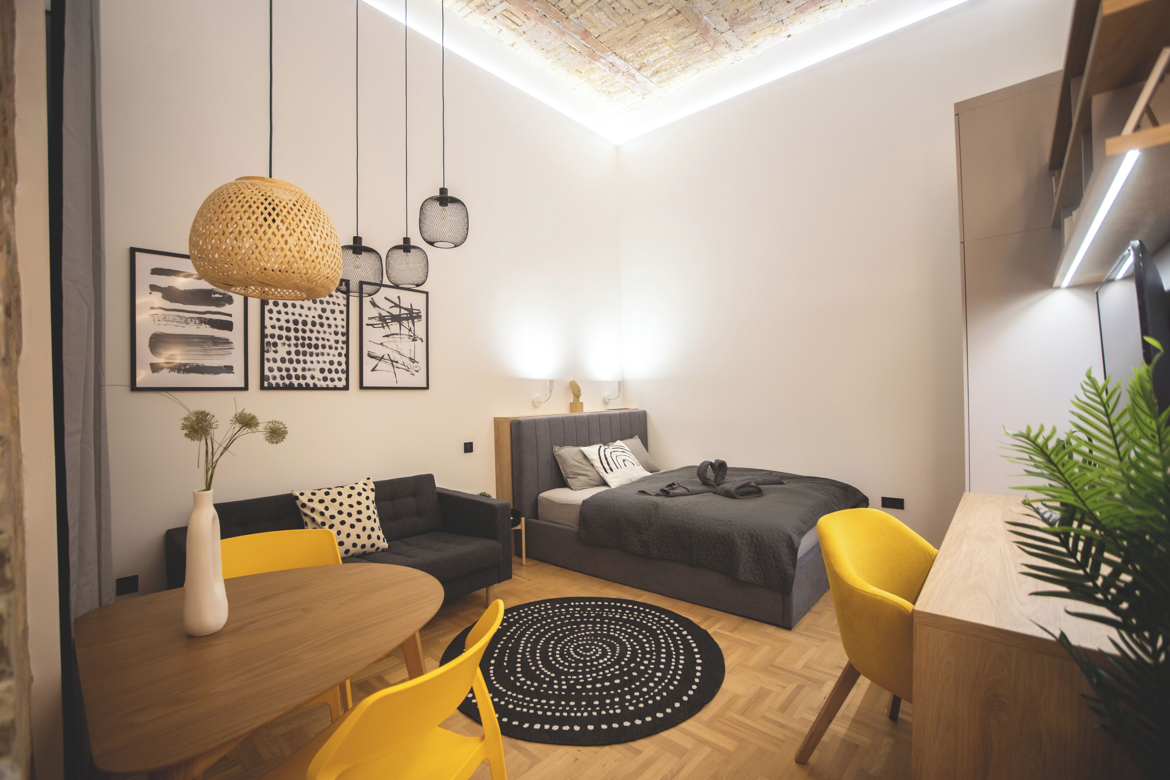 Ein modernes, kompaktes Wohnzimmer mit Bett, Sofa, Esstisch und Stühlen.