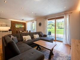 Ein modernes Wohnzimmer mit einem Ecksofa, einem Holztisch und einem Essbereich mit Tisch und Stühlen.