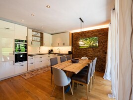 Eine moderne Küche mit weißen Schränken, einem Holztisch und einer Wand mit Ziegeln.