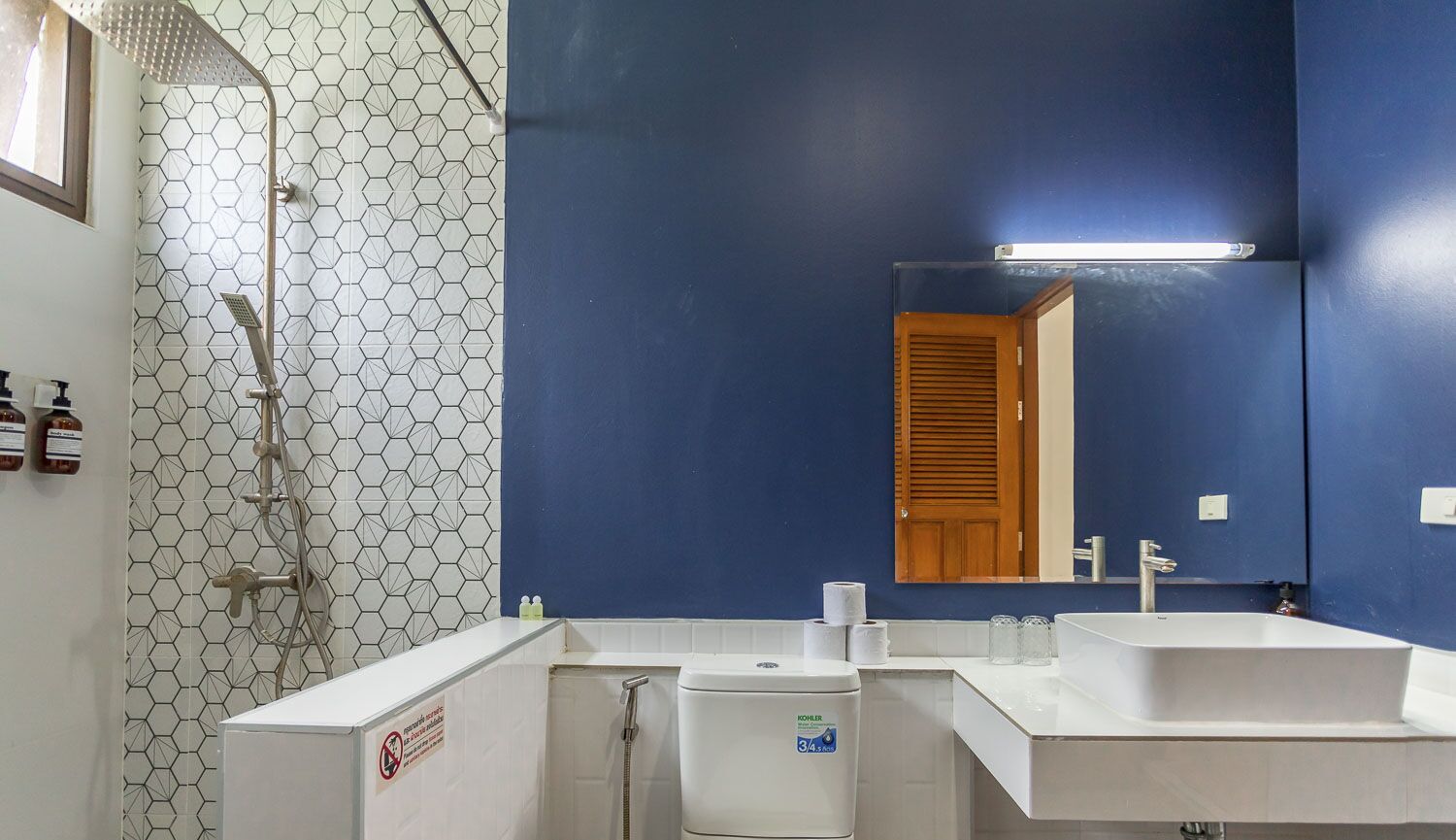A bathroom with a shower, two sinks, a toilet, and a mirror.