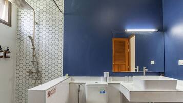 A bathroom with a shower, two sinks, a toilet, and a mirror.