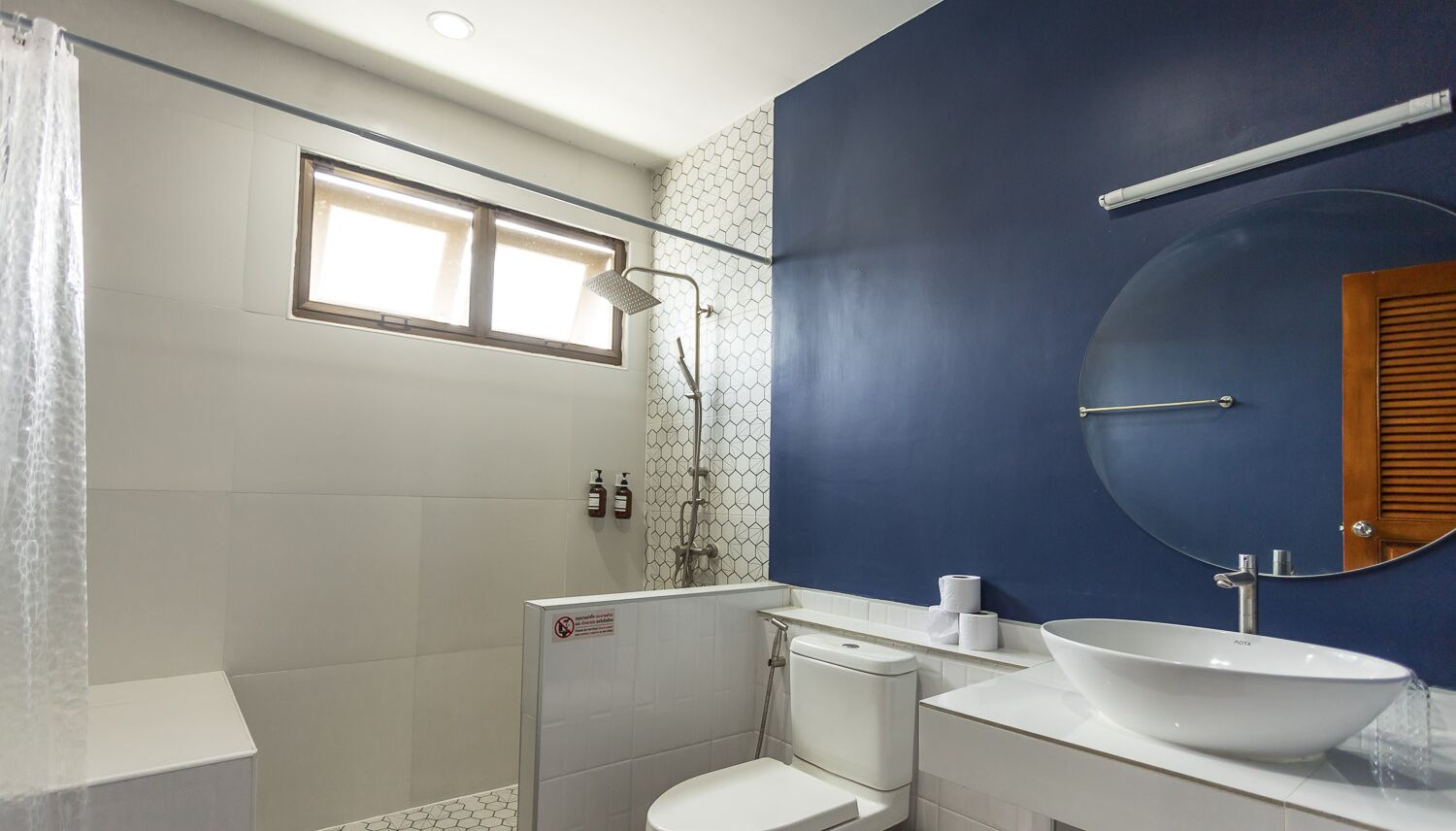 Ein Badezimmer mit Dusche, Toilette, Waschbecken und Spiegel.