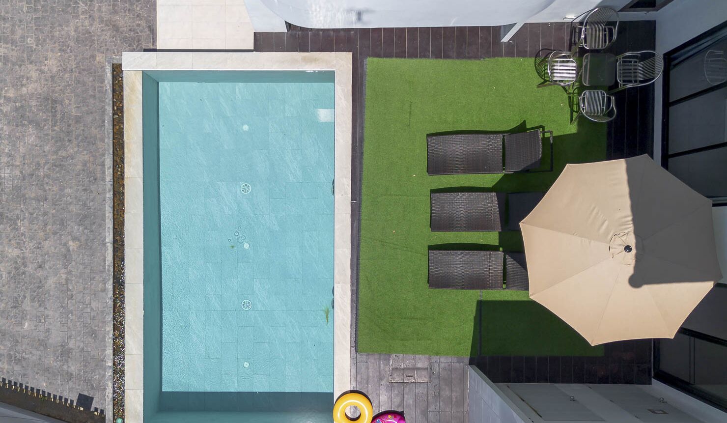 Ein Pool auf dem Dach mit einer grünen Rasenfläche und einer Sitzgelegenheit im Freien.