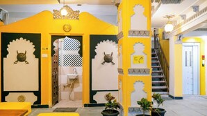 A yellow and white interior with a staircase, a sink, and potted plants. - The Hosteller Udaipur (Udaipur)