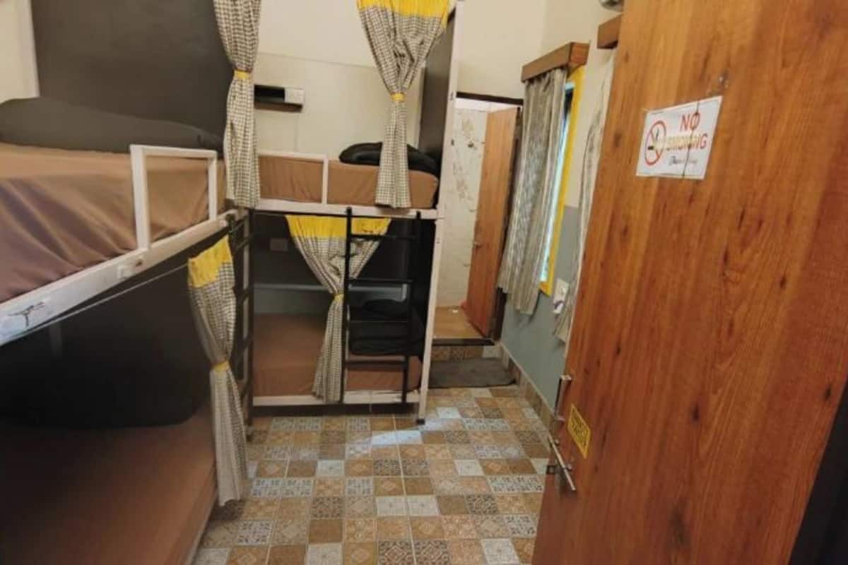 A compact room with a bunk bed, a desk, and a wardrobe.