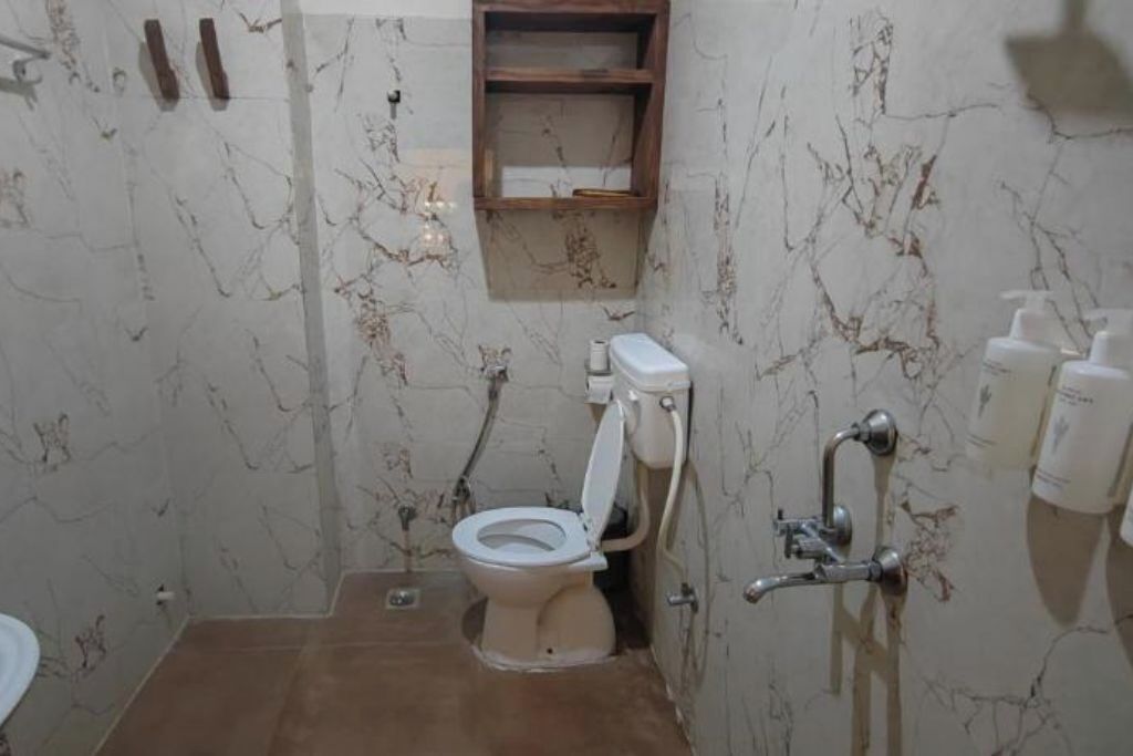 Une salle de bain avec des toilettes, une douche et une étagère au-dessus des toilettes.