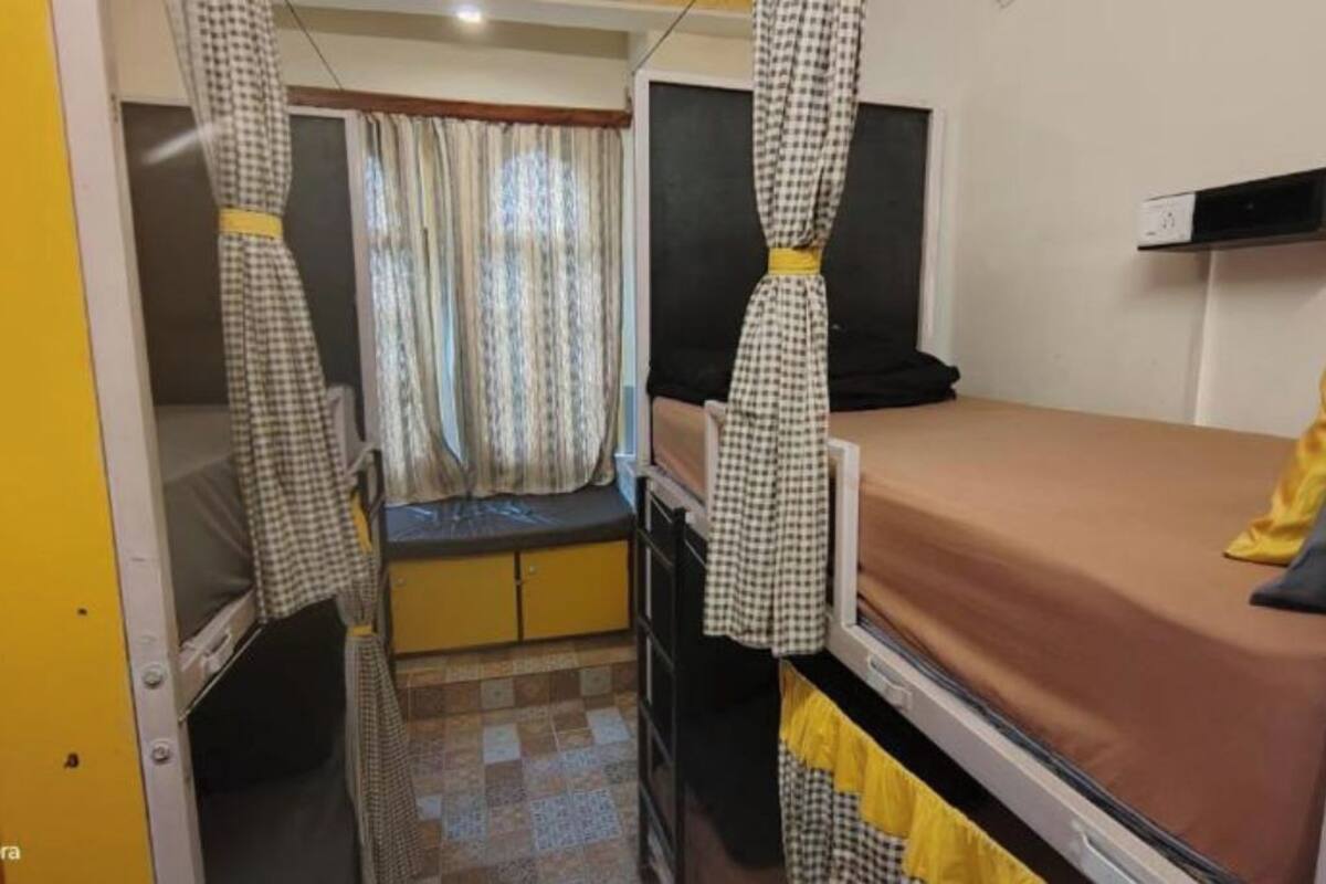 A compact room with a bed, a small desk, and a window with curtains.