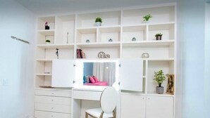 Ein heller Arbeitsbereich mit Schreibtisch, Stuhl und Regalen mit Dekorationen.