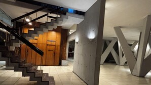Ein modernes Interieur mit einer Treppe, die zu einer Holztür führt, einer Betonwand und einem gefliesten Boden.