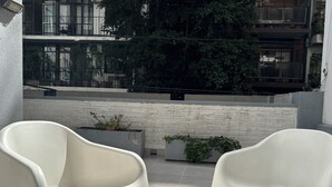 Ein Balkon mit zwei weißen Kunststoffstühlen, einer Ziegelwand und Topfpflanzen.