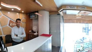 Zona d'entrada d'un hotel, amb una recepció, una zona d'espera i un ascensor.