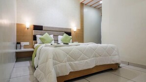 Una habitació d'hotel moderna amb un llit gran, taules de nit i il·luminació penjada a la paret.