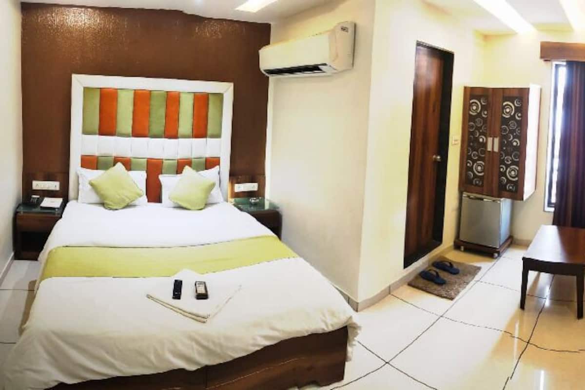 A hotel room with a bed, a desk, a TV, and a seating area.