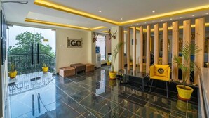 A modern lobby with a glass partition, a reception desk, and a seating area with yellow chairs. - The Hosteller Shimla (Shimla)