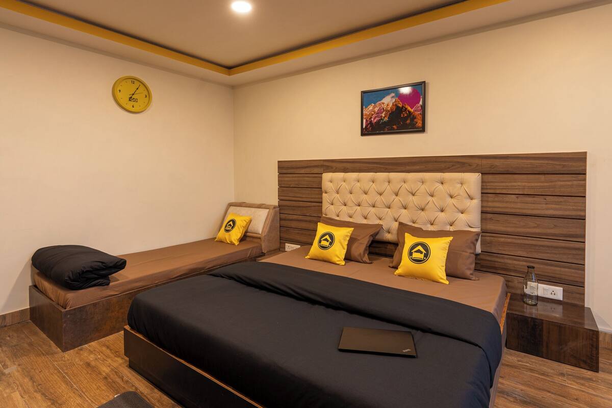 Une chambre à coucher moderne avec un grand lit, un petit canapé, une horloge et un tableau accroché au mur.
