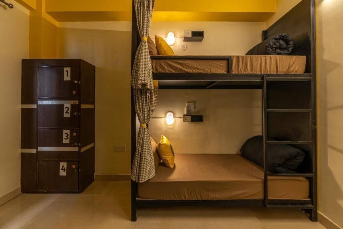 Une chambre avec un lit superposé, une armoire et un rideau.