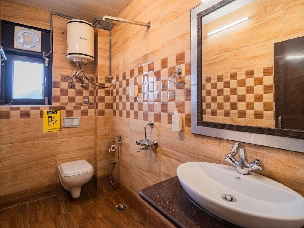 A bathroom with a checkered tile wall, a white sink, a toilet, and a shower.