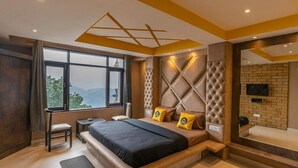 A modern bedroom with a large bed, a desk, and a view of the outdoors. - The Hosteller Shimla (Shimla)
