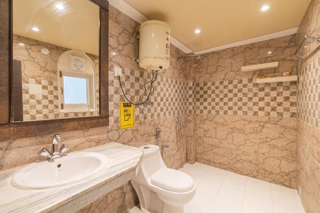 A bathroom with a marble wall, a sink, a toilet, and a shower.
