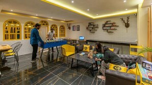 A lobby with a foosball table, seating area, and a wall with shelves and decorations. - The Hosteller Shimla (Shimla)