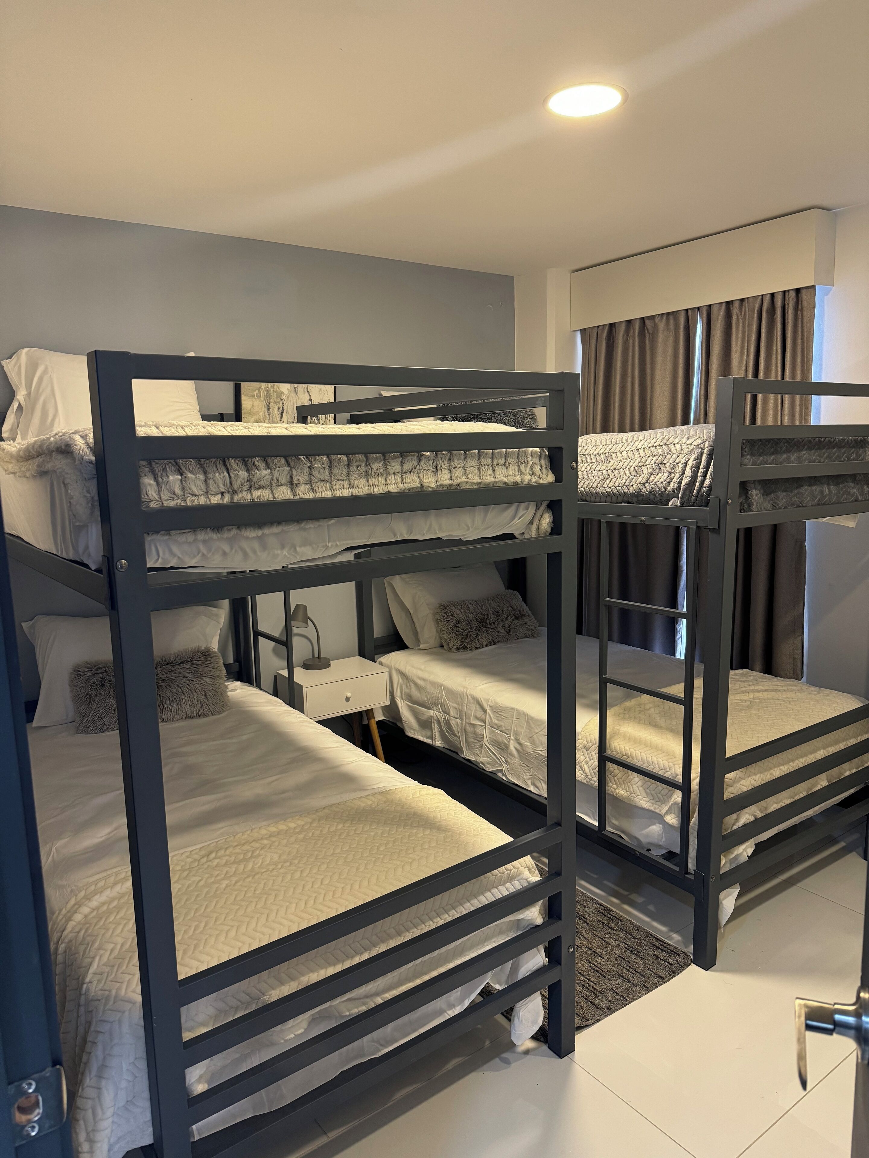 Habitación con literas, un escritorio y una ventana con cortinas.