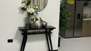 Een moderne keuken met roestvrijstalen apparatuur, een houten kast en een klein tafeltje met decoratieve objecten.