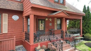 Una casa de madera roja con un porche, una decoración de estrella y un letrero que dice "Bly House".