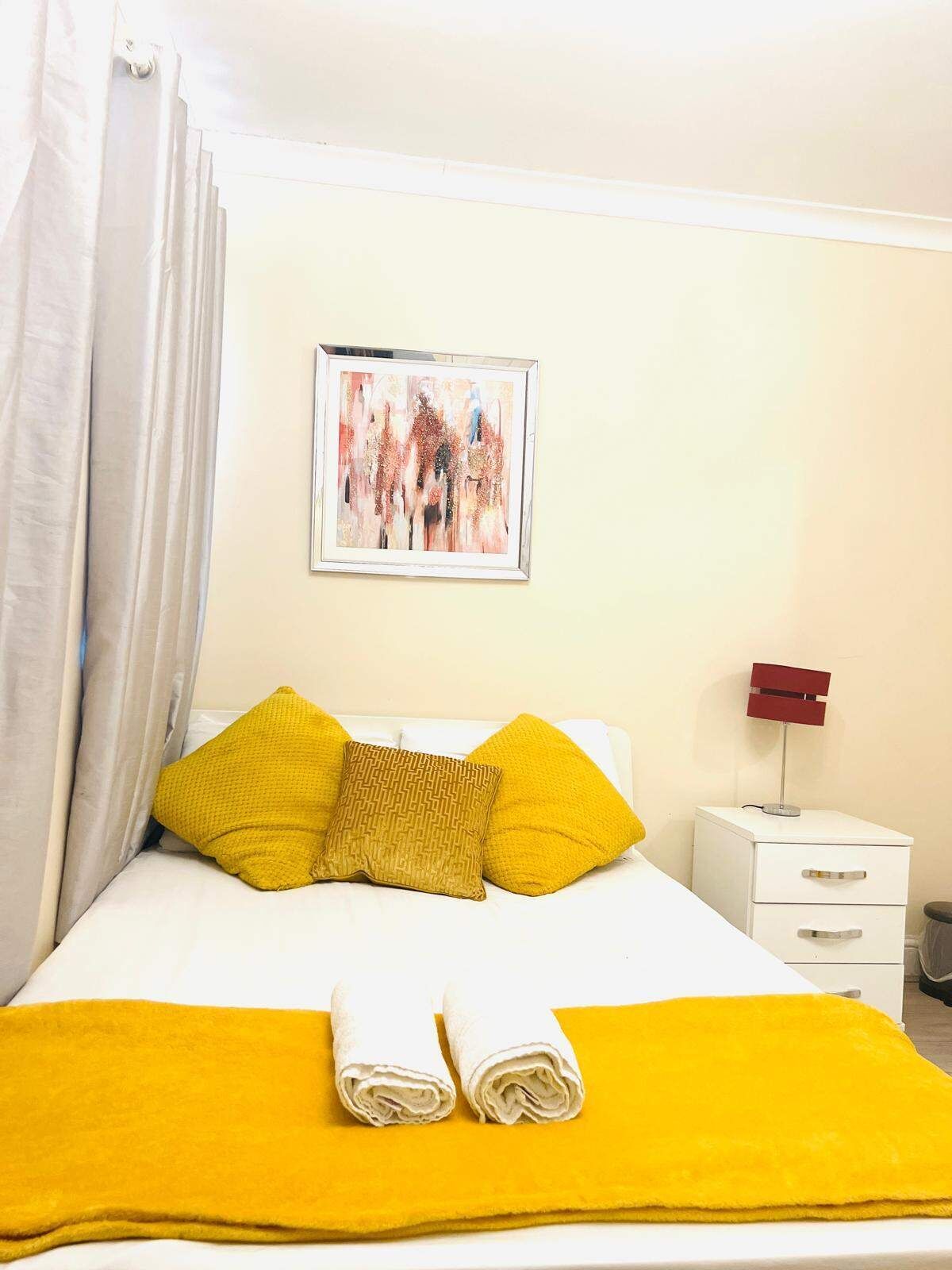 Una camera d'albergo con un letto, un quadro appeso al muro e un comodino con una lampada.